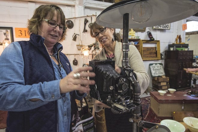 Past Into Light co-owner Michael Case shows antique enthusiast Julie Davis, left, a unique lamp made from plumbing components and an old camera during the Sage Farm Antiques 2nd Annual Autumn Spectacular Sunday at the Rochester Fairgrounds. Photo by John Huff/Fosters.com