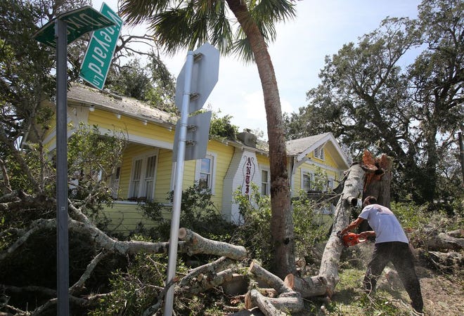A worker takes a chainsaw to a tree that fell on an antiques store at Vineyard Lane and North Dixie Highway in New Smyrna Beach. The roar of chainsaws was a familiar one Saturday, as area residents began the arduous task of cleaning up after Hurrican Matthew. News-Journal/NIGEL COOK