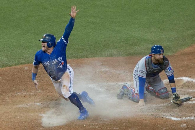 Toronto Josh Donaldson, left, celebrates after scoring the winning run on Sunday, leaving Texas catcher Jonathan Lucroy sprawled in the dirt. The Blue Jays finished off a sweep of the Rangers with a 7-6 win in 10 innings in Toronto.