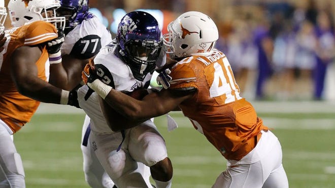 AUSTIN, TX - NOVEMBER 27: Aaron Green #22 of the TCU Horned Frogs is tackled by Naashon Hughes #40 of the Texas Longhorns at Darrell K Royal -Texas Memorial Stadium on November 27, 2014 in Austin, Texas. (Photo by Chris Covatta/Getty Images)