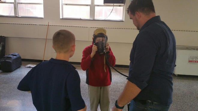St. Barbara seventh-grader Garrett Embree tries on a gas mask as his classmate, James Brown, looks on. (Submitted photo)