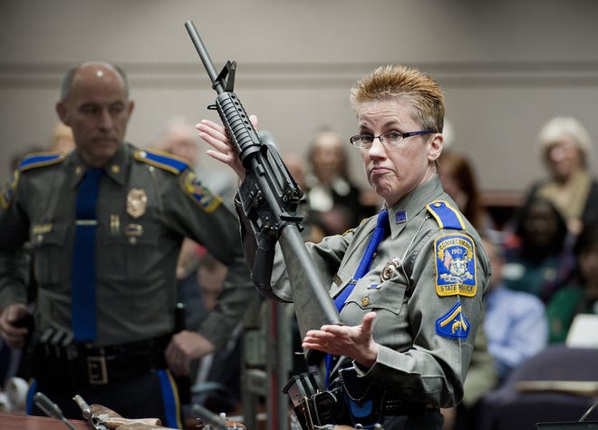 FILE - In this Jan. 28, 2013, file photo, firearms training unit Detective Barbara J. Mattson, of the Connecticut State Police, holds up a Bushmaster AR-15 rifle, the same make and model of gun used by Adam Lanza in the Sandy Hook School shooting, during a hearing of a legislative subcommittee, at the Legislative Office Building in Hartford, Conn. A judge on Friday, Oct. 14, 2016 dismissed a wrongful-death lawsuit by Newtown families against the maker of the rifle used in the Sandy Hook Elementary School shooting massacre, citing an embattled federal law that shields gun manufacturers from most lawsuits over criminal use of their products. (AP Photo/Jessica Hill, File)