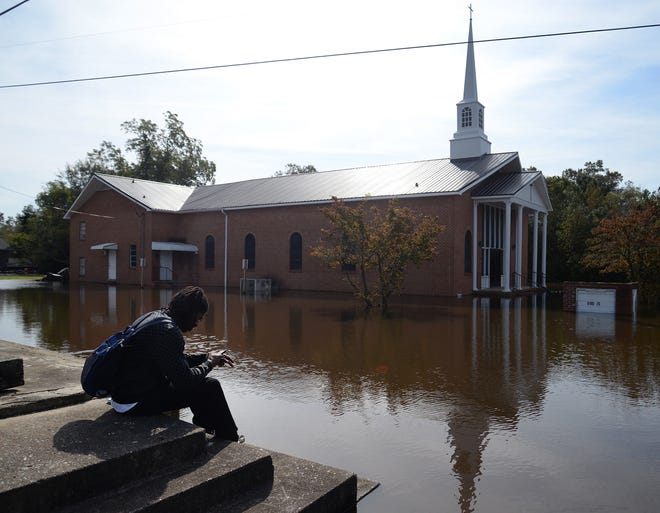 James Estep sits on a step along Shine Street as floodwater from the rain of Huurcane Matthew surrounds Faith Tabernacle Holy Church in Kinston, N.C., on Friday. (Zach Frailey/Daily Free Press via AP)