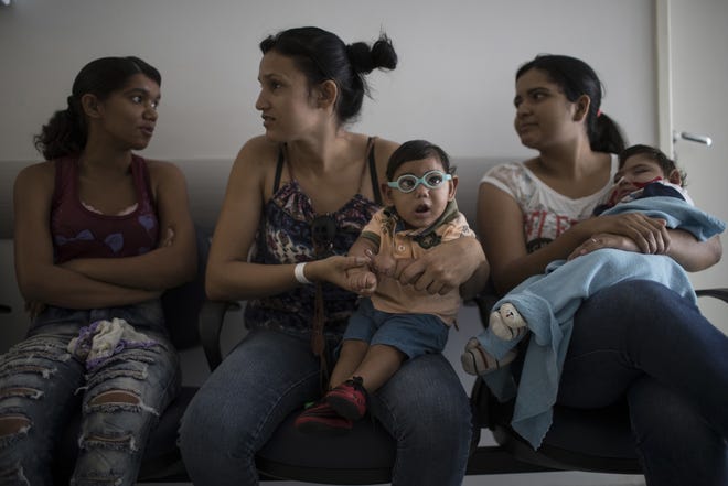 In this Sept. 27 photo, babies born with microcephaly Alexandro Julio, center, and Pedro Henrique, wait for their physical therapy session at the UPAE hospital in Caruaru, Pernambuco state, Brazil. A year after a spike in the number of newborns with the defect known as microcephaly, doctors and researchers have seen many of the babies develop swallowing difficulties, epileptic seizures and vision and hearing problems. (AP Photo/Felipe Dana)