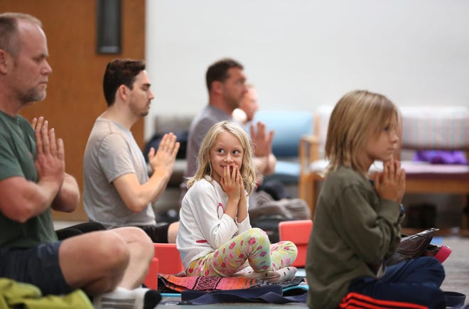 Rebecca Tennant, 6, can't help but giggle at her dad, Chris Tennant (left), along with brother Joshua Tennant (right) during a family yoga class at the Unitarian Universalist Church in Eugene on Saturday afternoon. Seven local yoga studios held a fundraiser for ShelterCare. (Collin Andrew/The Register-Guard)