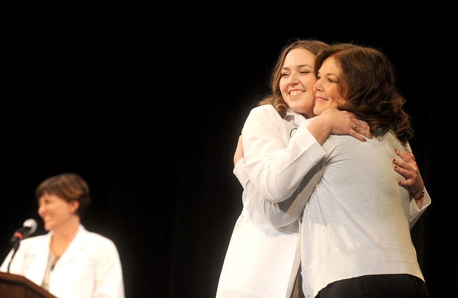 Maura Kenny, right, hugs her daughter, Shealyn Kenny, after helping her don a lab coat Sunday during the MU College of Veterinary Medicine’s White Coat Ceremony at the Missouri Theatre. The ceremony represents the transition from classroom to clinics and marks the midpoint in the professional curriculum.