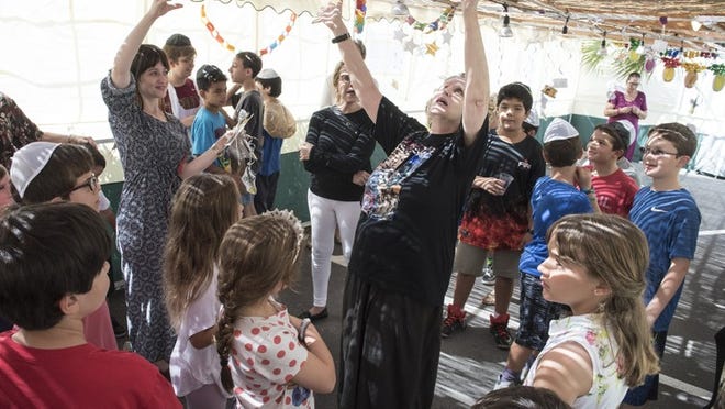 Tali Katz, (center) teaches children songs about decorating the sukkah Saturday at Palm Beach Synagogue. (Melanie Bell / Daily News)
