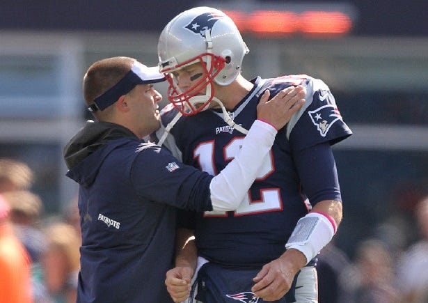 Tom Brady gets a slap on the shoulders pads from Josh McDaniels after running onto the field for pregame warm ups against the Bengals on Sunday.