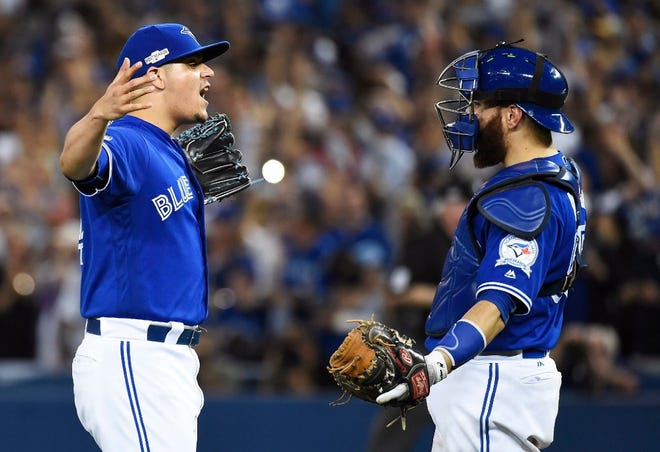 Reliever Roberto Osuna and catcher Russell Martin celebrate after the final out of Toronto's win over Cleveland.