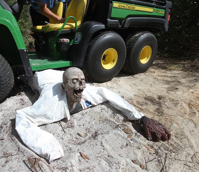 An unfortunate soul tries to crawl out from under a city off-road vehicle Thursday at Deltona's Dewey Boster Sports Complex. Zombies will haunt thousands at this weekend's Spooktacular. NEWS-JOURNAL/DAVID TUCKER