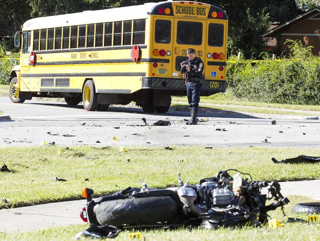 Ocala Police Department Officer Charles Hunt takes pictures at the scene of a fatal accident Thursday afternoon involving a school bus and a motorcycle. (Doug Engle/Star-Banner)