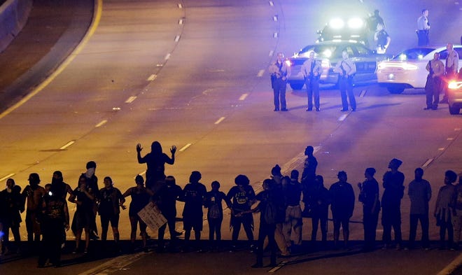 In this Thursday, Sept. 22, 2016 file photo, protesters block I-277 during a third night of unrest following Tuesday's police fatal shooting of Keith Lamont Scott in Charlotte, N.C. (AP Photo/Gerry Broome, File)