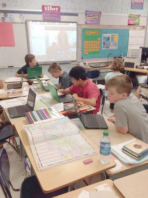 ’Skyping’ with a class at an unknown location via the smartboard on the wall, Wethersfield sixth graders exchange questions and answers, then do research using their Chromebook laptops and real maps to determine the location of the other school. At work from back to front are Evan Krause, Matthew Senteney, Orlando Turcios and Liam Singleton.