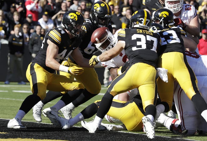 Wisconsin running back Corey Clement, center, fumbles the ball into the end zone between Iowa defenders Ben Niemann (44), Jaleel Johnson (67) and Brandon Snyder (37) during the first half of Saturday's game in Iowa City, Iowa. Iowa recovered the ball. (AP Photo/Charlie Neibergall)