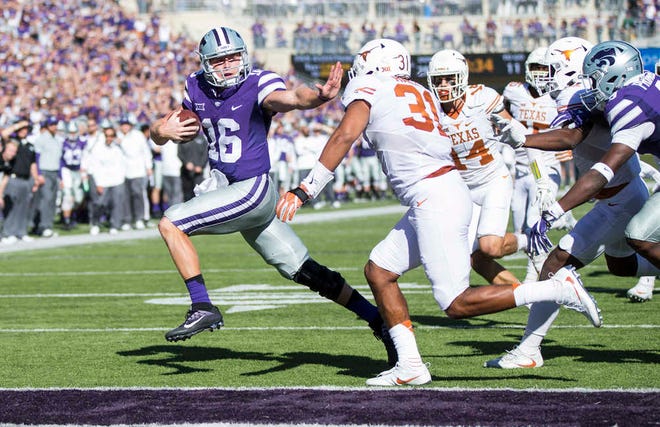 K-State quarterback Jesse Ertz holds out his hand to avoid the arms of Texas safety Jason Hall on Saturday at Bill Snyder Family Stadium.