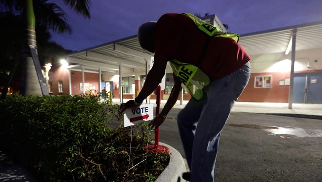 An election worker puts up a "Vote" sign outside of a polling station on the first day of early voting in Miami-Dade County for the general election, Monday, Oct. 24, 2016, in Miami. (Lynne Sladky/Associated Press)