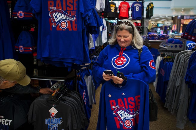 Nancy Phillips texts friends while picking up Chicago Cubs merchandise for them at Scheels on Monday. Phillips said the adrenaline high from attending the game Saturday when the Cubs advanced to the World Series is just now starting to wear off. Ted Schurter/The State Journal-Register