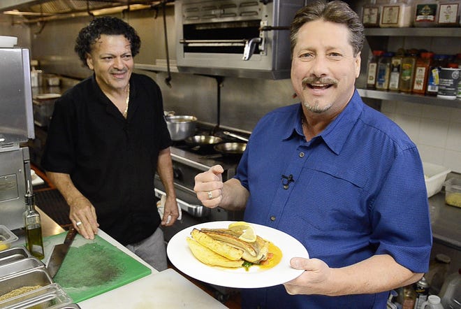 Eat This! host Chuck Thomas holds the Pan-Fried Branzino made by the Canal Street Grille's Chef Modesto (background), which is the featured dish on this week's episode of Eat This!