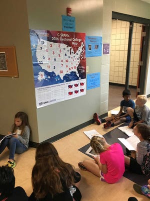 In this photo provided by Halie Miller, taken Sept. 26, 2016, students in Halie Miller's fourth grade class at Glacier Ridge Elementary School in Dublin, Ohio, use an Electoral College map to create different combinations of numbers to get to the magic number of 270 electoral votes needed for victory as part of a math assignment. (Halie Miller via AP)