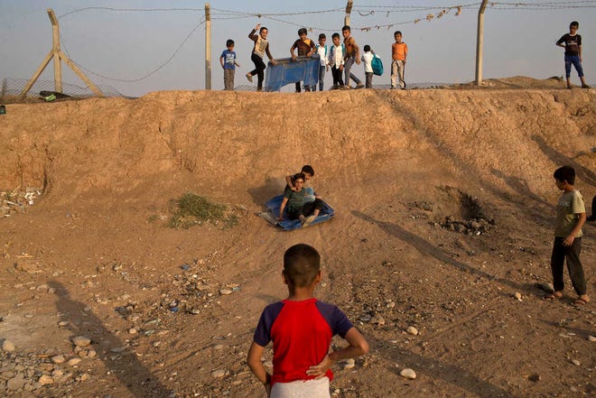 Children use a piece of plastic to slide down a slope at the Baharka camp for displaced persons on the outskirts of Irbil, Iraq, Tuesday, Oct. 25, 2016. Nearby Mosul, the largest city controlled by the Islamic State group, is still home to more than 1 million civilians. The government and international aid groups fear that a sudden mass exodus will overwhelm the few camps set up on its outskirts. (AP Photo/Marko Drobnjakovic)
