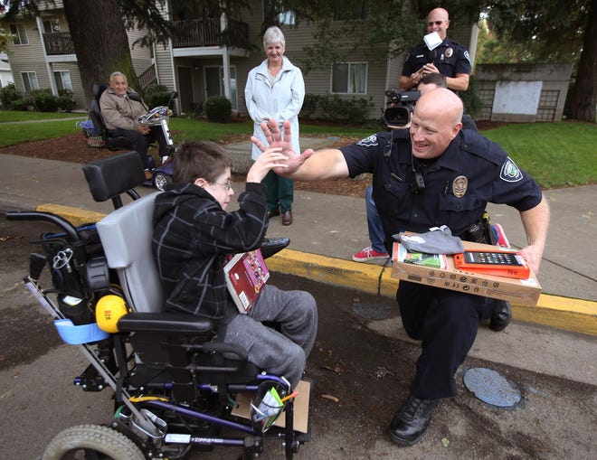 Springfield motorcycle officers Matt Bohman (left) and Mike Massey escort Brayden Mitchell from his bus stop to his home after meeting him and giving him a computer. Mitchell’s was stolen, along with his Kindle Fire, from his grandparents’ apartment. (Chris Pietsch/The Register-Guard)
