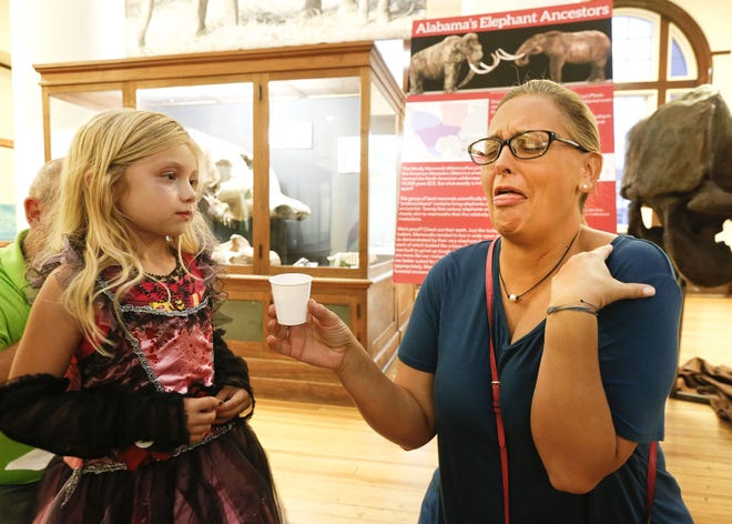 Laken Hodges watches while her aunt, Kristin Graham, eats bugs inside the Alabama Museum of Natural History during a night that included ghost tours of the University of Alabama campus and other frightful experiences involving bugs and creepy things Tuesday. Graham had just eaten a cricket cooked in cajun spice. Staff Photo/Gary Cosby Jr.