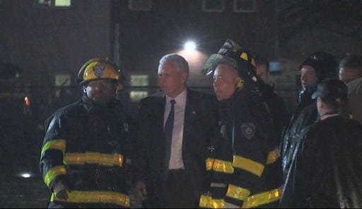 Republican vice presidential candidate Indiana Gov. Mike Pence talks with firefighters at New York's LaGuardia Airport after his campaign plane slide off the runway while landing on Thursday, Oct. 27, 2016. (TV Network Pool via AP)