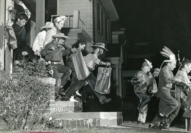 Trick or treaters rush from house to house with their Halloween loot in Providence's Elmwood section in 1957. Cowboy costumes were popular during that decade. Providence Journal File Photo