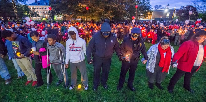 Mourners hold hands and candles during a vigil held Wednesday at Hyannis Village Green in memory of local youths killed in a car crash. PHOTO BY ALAN BELANICH