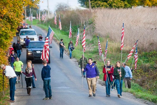 Farmington Central High School students and staff as well as other volunteers parade down East Park Road southeast of Farmington to plant flags along the road Thursday, honoring area soldier Sgt. Douglas Riney, 26, of Fairview, who died Oct. 20 in Afghanistan.