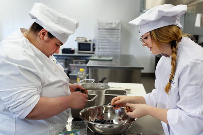 Burlington High School senior Baylee Howell, 18, and junior Rylee Reid, 17, students in the school’s culinary arts class, separate grapes from their stems Thursday as they work on a Concord grape sorbet with rosemary and black pepper while preparing for today’s Southeast Iowa Iron Chef Competition.