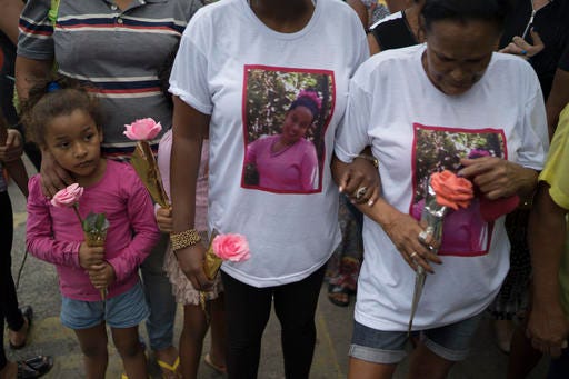 Relatives and friends hold roses during the burial service of Bruna Lace de Freitas, who was killed two days earlier by a stray bullet when she was inside her home, in Rio de Janeiro, Brazil, Friday, Oct. 28, 2016. The Brazilian Forum on Public Security says in its 10th annual report that in 2015 more people were murdered in Brazil than have been killed in war-torn Syria. (AP Photo/Leo Correa)