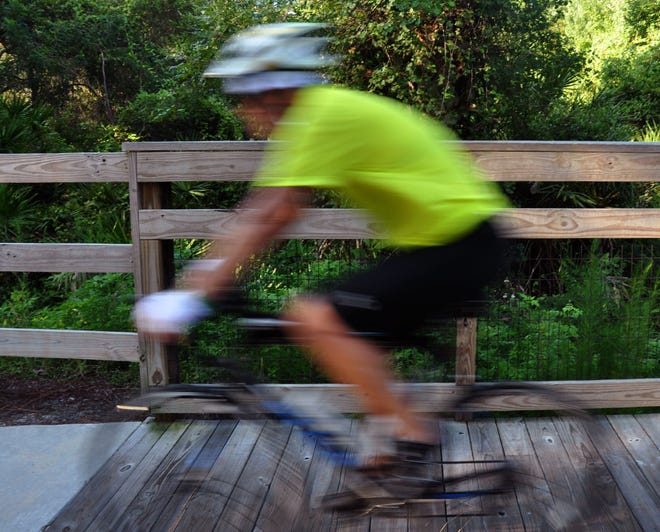 News-Journal/PETER BAUER A rider speeds along the Spring to Spring Trail, in Deltona, on Friday morning, August 1, 2014.