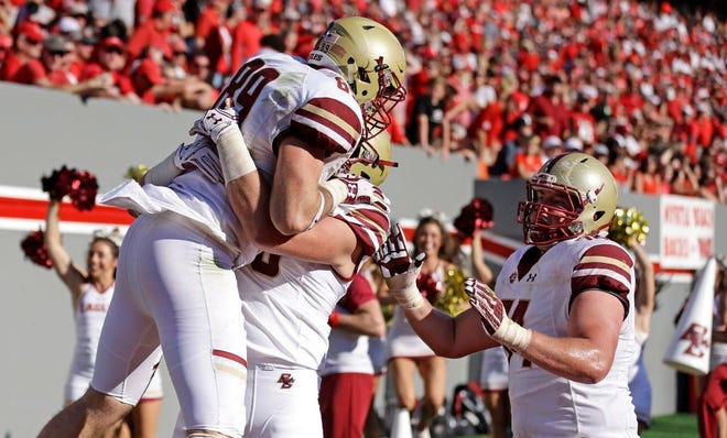 Boston College tight end Michael Giacone, center, lifts tight end Tommy Sweeney (89) as offensive lineman Jimmy Lowery comes in at right, following Sweeney's touchdown against North Carolina State during the second half of an NCAA college football game in Raleigh, N.C., Saturday, Oct. 29, 2016. Boston College won 21-14. (AP Photo/Gerry Broome)