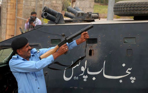 A Pakistani police officer fires tear gas shell to disperse supporters of Imran Khan, who are attempting to reach Khan's residence in Islamabad, Pakistan, Sunday, Oct. 30, 2016. Pakistani police used tear gas and batons to confront stone throwing supporters of cricketer-turned-politician Imran Khan, ahead of a planned protest next week. (AP Photo/Anjum Naveed)