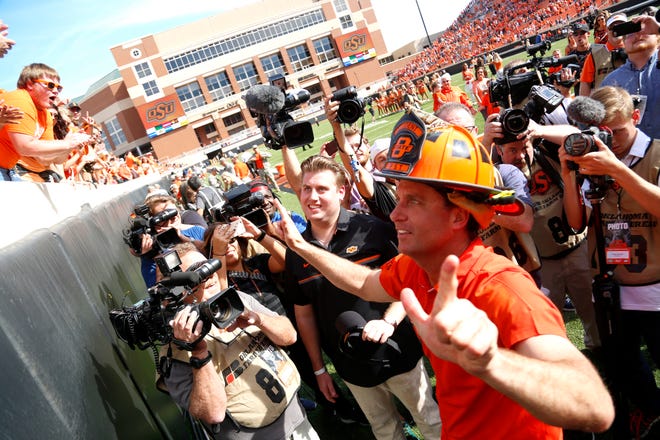 Oklahoma State head coach Mike Gundy celebrates with fans by wearing a fireman's hat following a college football game between the Oklahoma State University Cowboys (OSU) and the West Virginia Mountaineers (WVU) at Boone Pickens Stadium in Stillwater, Okla., Saturday, Oct. 29, 2016. Oklahoma State won 37-20. Photo by Sarah Phipps, The Oklahoman