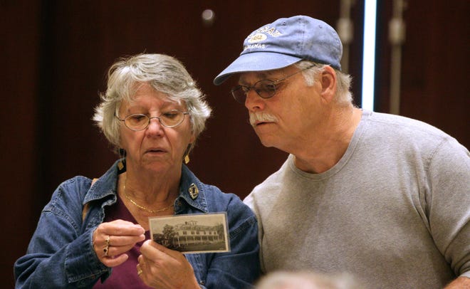 Stephen DiNobile, of North Kingstown, looks over the shoulder of his wife, Denise Boisvert, as they hunt for vintage postcards at the Rhode Island Postcard Club's annual show Sunday at the Crowne Plaza in Warwick. The Providence Journal / Kris Craig