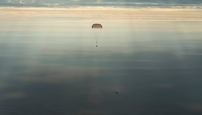 The Soyuz MS-01 spacecraft descends beneath a parachute with NASA astronaut Kate Rubins, Russian cosmonaut Anatoly Ivanishin of Roscosmos, and astronaut Takuya Onishi of the Japan Aerospace Exploration Agency (JAXA) near the town of Zhezkazgan, Kazakhstan Sunday. A Russian Soyuz space capsule has landed in Kazakhstan, bringing back three astronauts from the United States, Japan and Russia back to Earth from a 115-day mission aboard the International Space Station. (NASA/Bill Ingalls)