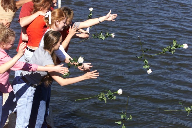 Classmates of Stirling Belz throw flowers into Callaway Bayou in his honor. Belz died when hsi car overturned into the bayou in 2001. NEWS HERALD FILE PHOTO
