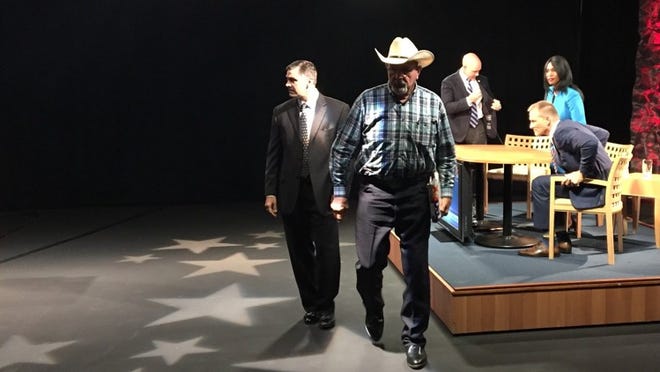 Paul Parton (in hat), a former business associate of Democratic congressional candidate Randy Perkins (seated), leaves the WPTV Channel 5 studio after a congressional debate. At the table, from the right, are the U.S. House District 18 candidates, Democrat Randy Perkins, no-party candidate Carla Spalding and Republican Brian Mast. (George Bennett/The Palm Beach Post)