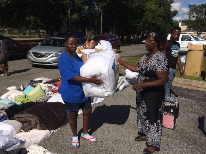 Janie Crawford, right, founder and president of Ivory’s Place, gives a comforter to Jeanita Washington during Project Blessing Saturday at Village Green/Forest Green. The nonprofit gave away more than $25,000 in household items.Cleveland Tinker/Special to the Guardian