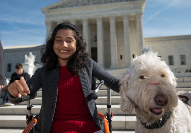 — AP photo by MOLLY RILEY 

Ehlena Fry, 12, of Michigan sits with her service dog, Wonder, while speaking to reporters Monday outside the Supreme Court in Washington following oral arguments on a case where Fry, who has cerebral palsy, wants to sue school officials for refusing to let her bring a service dog to class.