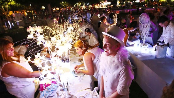 Matthew Levi, right, of West Palm Beach, smiles with family and friends after helping decorate during Le Diner en Blanc in downtown West Palm Beach on November 10, 2015. (Richard Graulich / The Palm Beach Post)