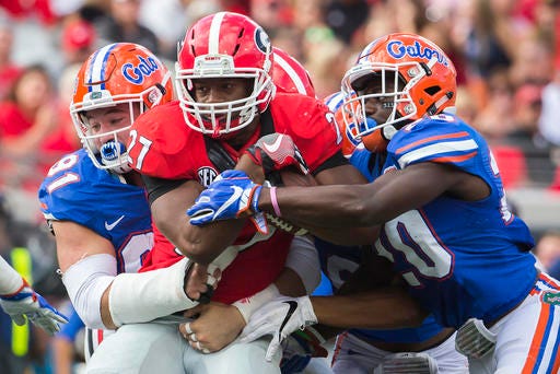 FILE - In this Saturday, Oct. 29, 2016, file photo, Florida defensive back Marcus Maye (20) and defensive lineman Joey Ivie (91) tackle Georgia running back Nick Chubb (27) during the first half of an NCAA football game in Jacksonville, Fla. Even with talented running backs Nick Chubb and Sony Michel, Georgia is still looking for answers on offense after being held to a season-low 164 yards in last week's 24-10 loss to Florida. The Bulldogs are preparing to play at Kentucky on Saturday. (AP Photo/Stephen B. Morton, File)