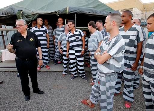 FILE - In this , June 23, 2012, file photo, inmates gather next to Maricopa County Sheriff Joe Arpaio as he walks through a Maricopa County Sheriff's Office jail called "Tent City" in Phoenix. Arpaio disbanded a SWAT team that focused on handling dangerous jail inmates at a time when the elite unit was in high demand due to a spike in assaults by inmates on guards, records show. Arpaio folded the Special Response Team in September as part of $8 million in budget cuts to cover skyrocketing legal costs from a racial-profiling case against the sheriff's office. (AP Photo/Matt York, File)