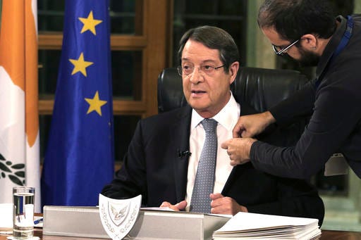 A television crew member adjusts a microphone on the jacket of Cyprus President Nicos Anastasiades before a nationally televised news conference at the Presidential Palace in Nicosia, Cyprus, Friday, Nov. 4, 2016. The president of ethnically divided Cyprus says Turkey's input will be pivotal in overcoming key obstacles preventing a reunification deal. Nicos Anastasiades, a Greek Cypriot, says he and breakaway Turkish Cypriot leader Mustafa Akinci have made significant progress on numerous issues making an envisioned federation workable. (Yiannis Kourtoglou/Pool Photo via AP)