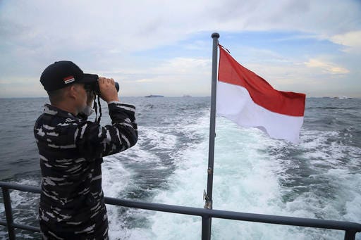 An Indonesian marine uses binoculars from the deck of a rescue ship during a search operation for dozens of people still missing after an overcrowded speedboat capsized off Batam, Indonesia, Thursday, Nov. 3, 2016. Indonesian police on Thursday arrested two crewmen of the speedboat as rescuers continued searching for the dozens of passengers still missing. (AP Photo/M Urip)