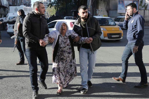People help an elderly person after an explosion in southeastern Turkish city of Diyarbakir, early Friday, Nov. 4, 2016. A large explosion hit the largest city in Turkey's mainly Kurdish southeast region on Friday, wounding several people, the state-run Anadolu Agency reported. Turkish authorities have imposed a temporary blackout on coverage of the blast occurred in Diyarbakir on Friday, citing public order and national security reasons. (AP Photo/Mahmut Bozarslan)