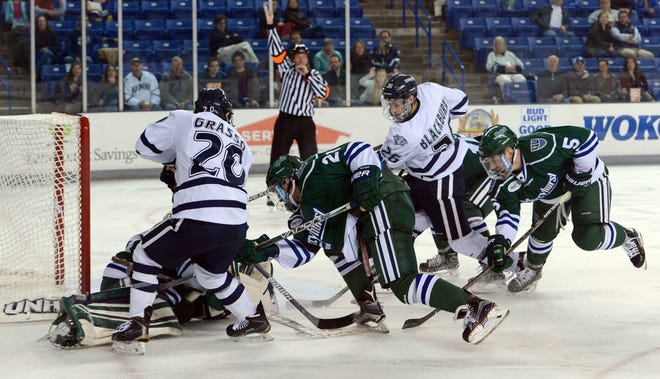 University of New Hampshire players Patrick Grasso (20) and Liam Blackburn battle two Mercyhurst defenders in front of Lakers goalie Colin DeAugustine during the Wildcats' 3-0 win on Saturday night at the Whittemore Center in Durham. Blake Gumprecht/Fosters.com