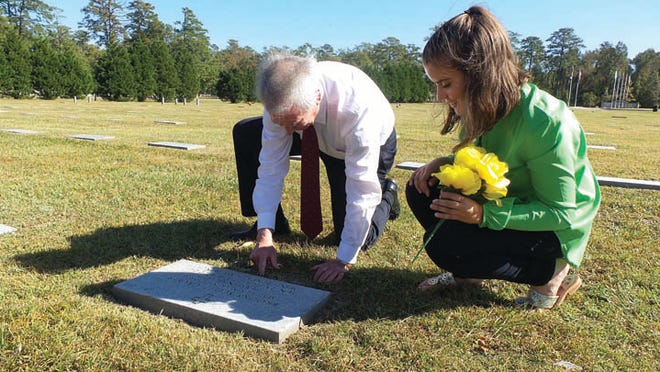 Congressman Walter Jones buries a Challenge Coin in front of Maj. Brooks Gruber's grave, showing his daugher, Brooke Gruber, where she can dig it back up years from now. Photo by Amanda Thames / The Daily News